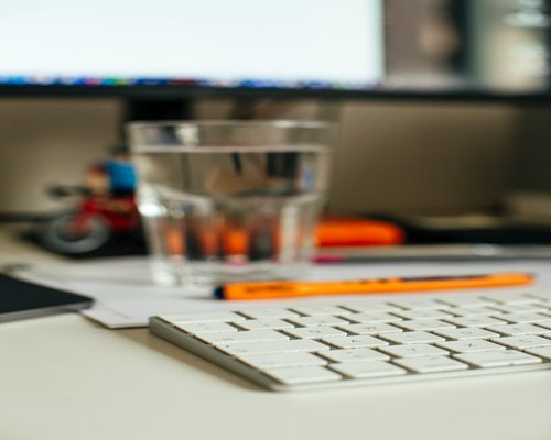 A clean workspace desk with an educational notebook and a glass of refreshing clear water
